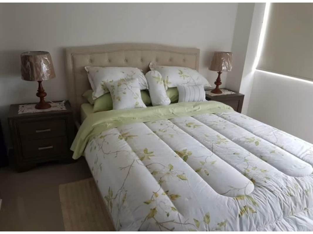 Bedroom with upholstered headboard, nightstand, lamp, and window PH Sky Park Carrasquilla Panama