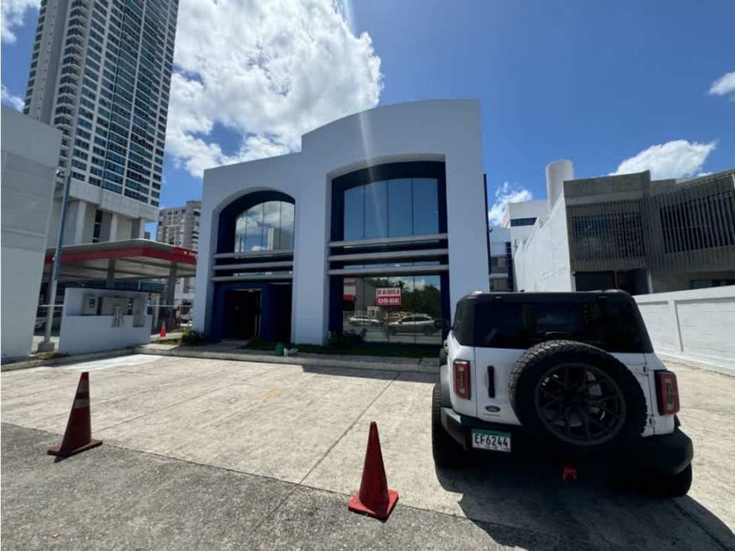 Two-story commercial property with curved roofline, arched windows, parking in front in Costa del Este