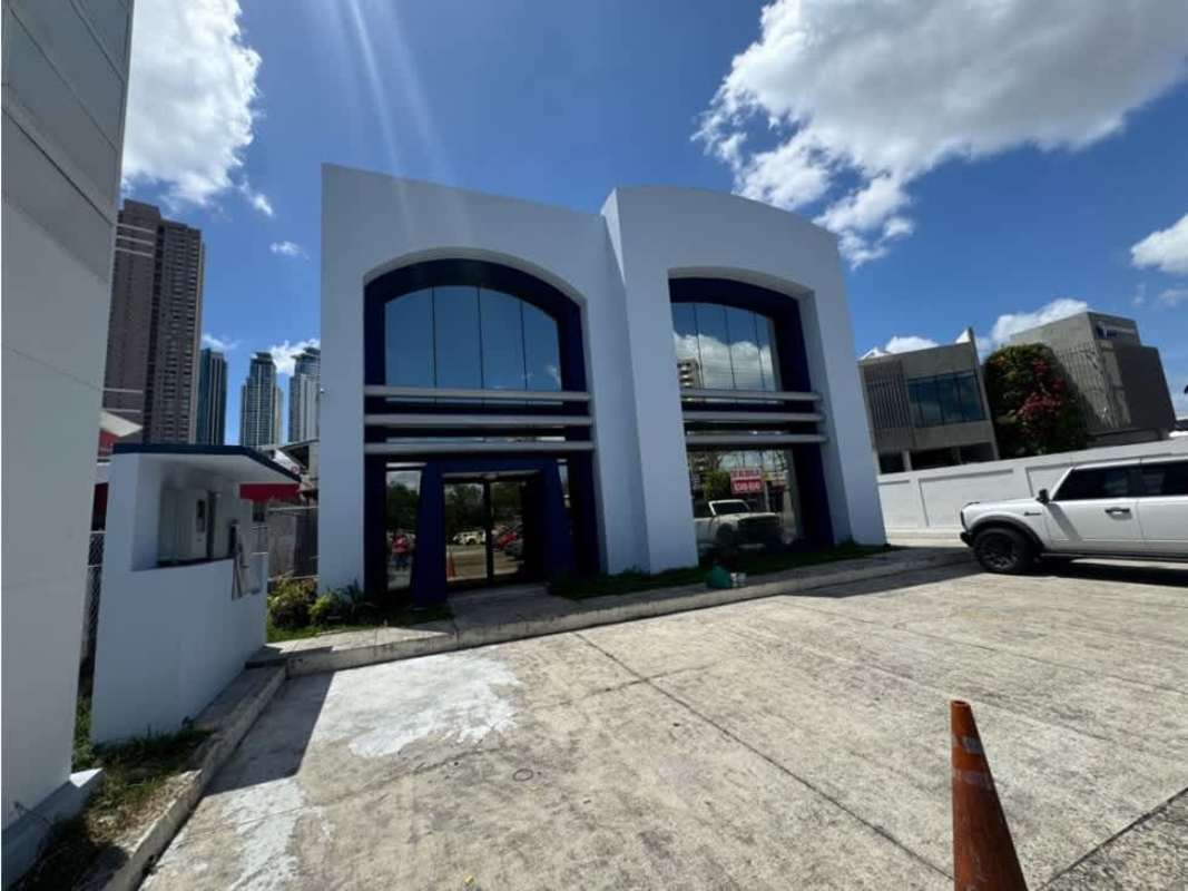 Two-story commercial office building with large arched mirrored windows and parking lot Costa del Este