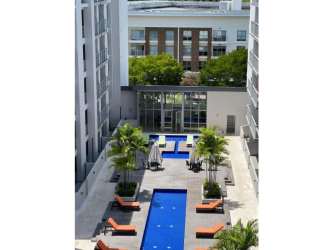 Apartment exterior with large swimming pool, deck chairs, palm trees at PH Mosaic Panama Pacifico