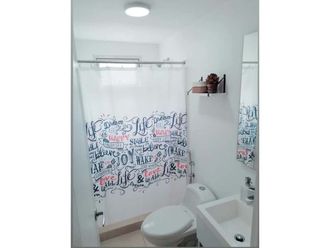 Modern bathroom with shower curtain, sink, toilet in PH Panamá Residences Panama City