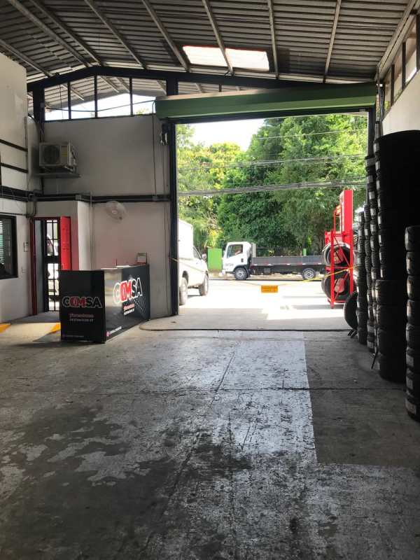 Interior industrial workshop area with open garage door, concrete floor, high ceilings in warehouse Santa Elena Panama