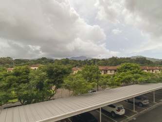 Kitchen with granite countertops, dark wood cabinets, microwave and fridge in 1BR apartment Panama Pacifico