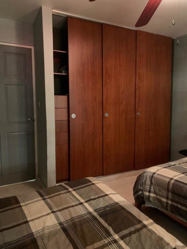 Guest bedroom with sliding closet doors and ceiling fan at Brisas del Golf Panama City