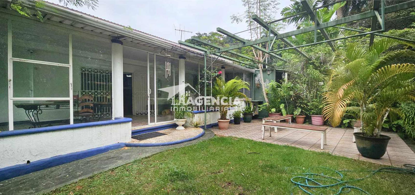 Shaded outdoor terrace patio facing tropical landscaped fenced yard Panama