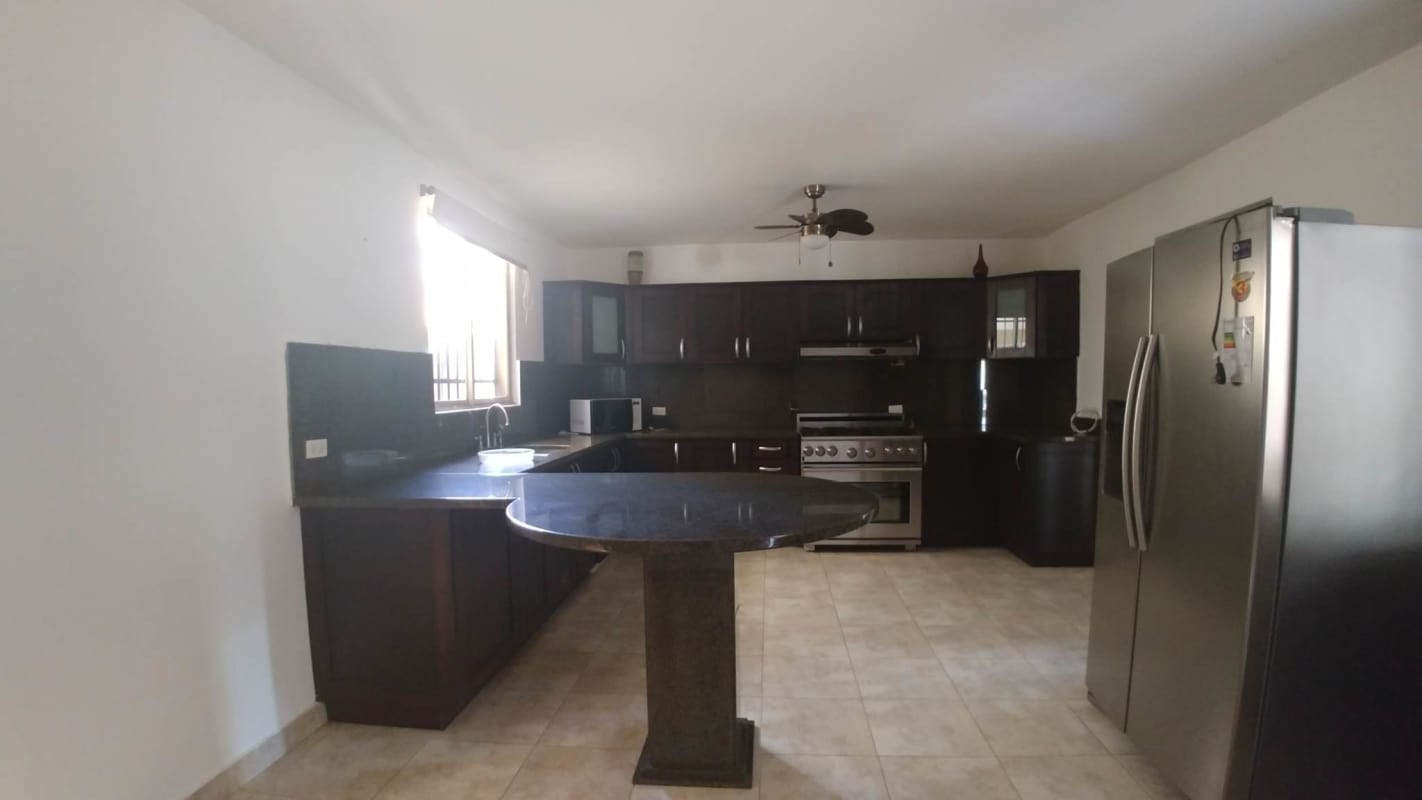 Kitchen with granite countertops, island, dark cabinets and stainless appliances in Condado del Rey Panama