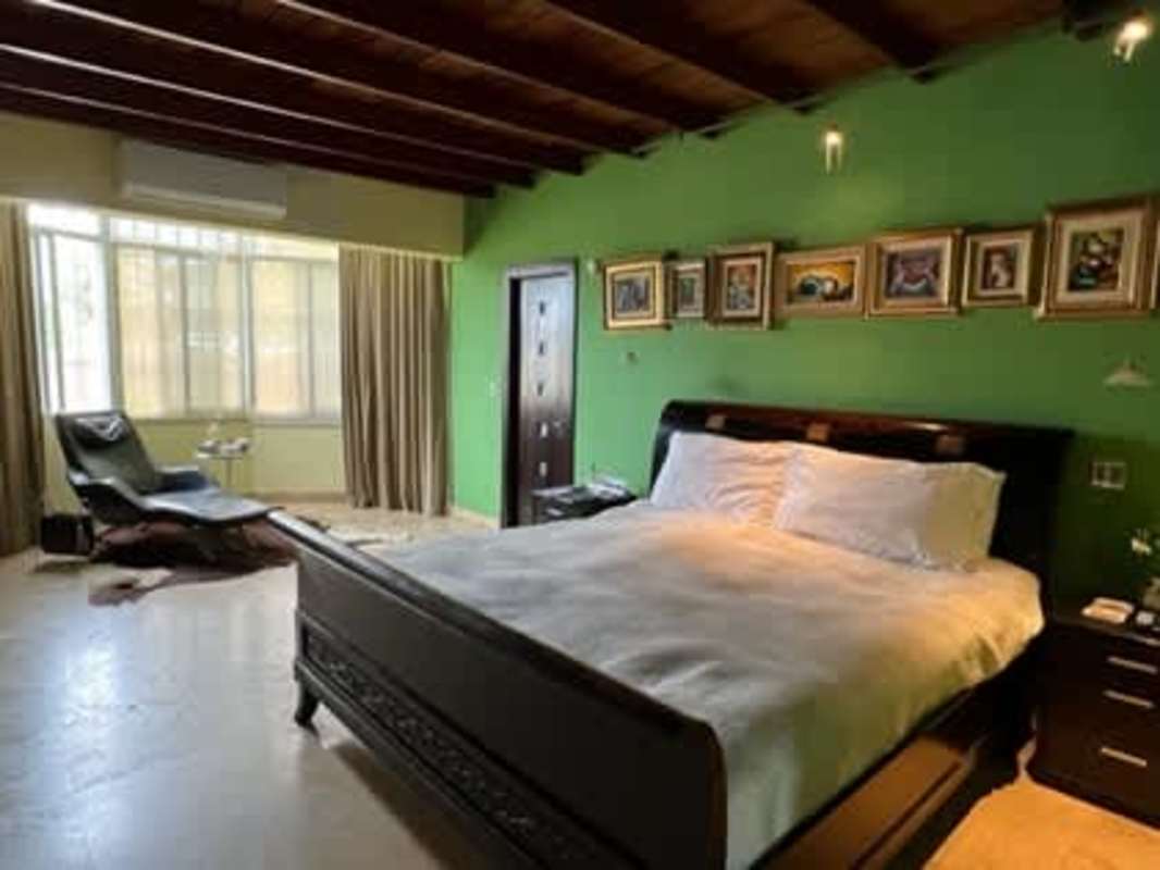 Bedroom with wood beamed ceiling, green wall, large window, AC unit San Francisco Panama