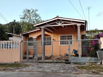 Single storey peach bungalow with porch, gated fence, and plants in La Chorrera Panama