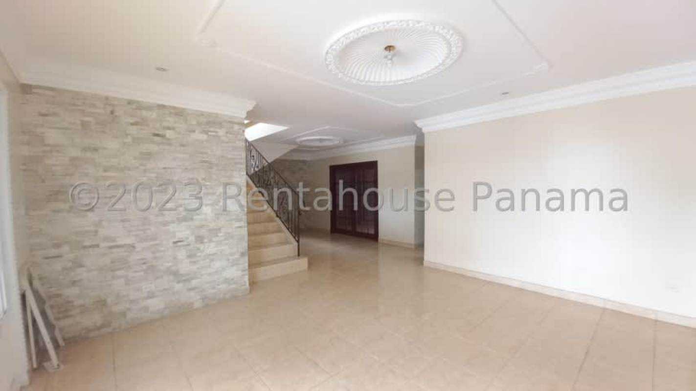 Spacious living room with tile floors, stone accent wall, staircase with iron railing Residencial San Antonio Panama