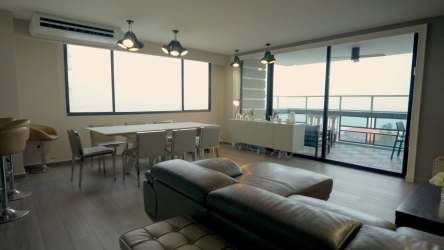 Open-plan living dining area with beachfront balcony and ocean views in Coronado Panama apartment