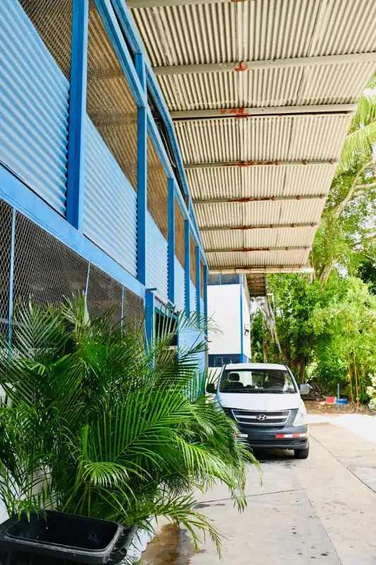Industrial complex exterior with blue siding, tropical plants and parking Pueblo Nuevo Panama