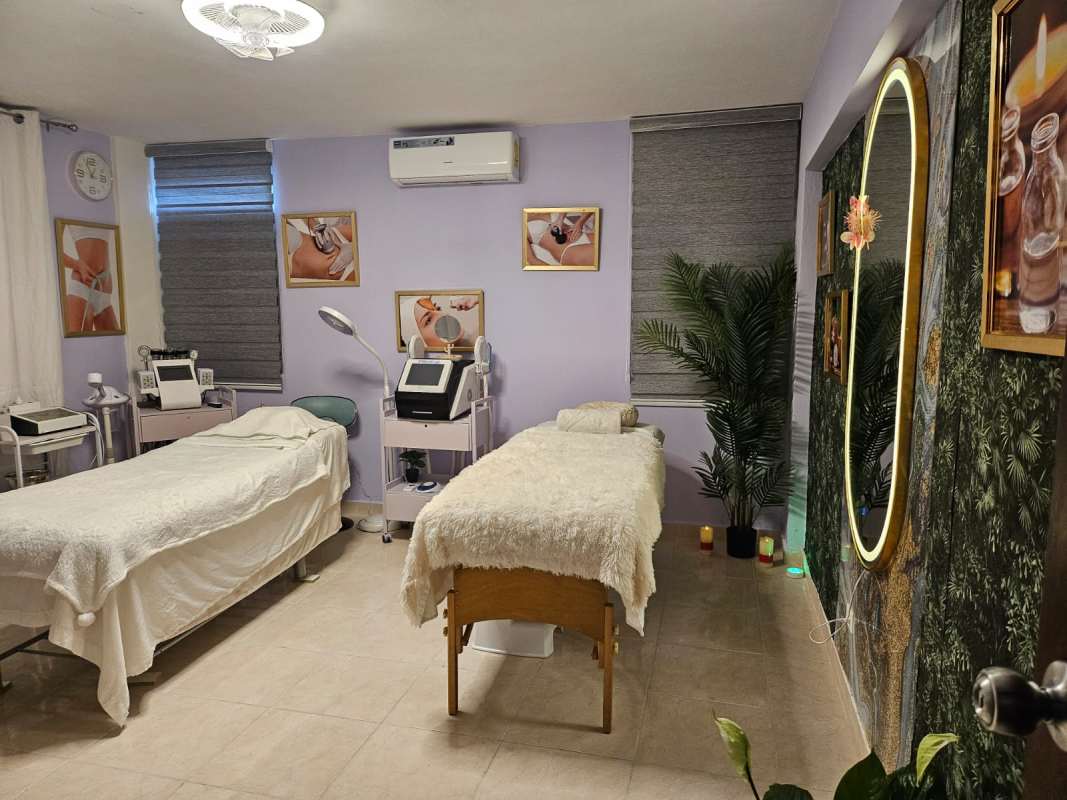 Spa treatment room with two massage beds, medical spa equipment, illuminated mirror in Via España El Carmen Panama