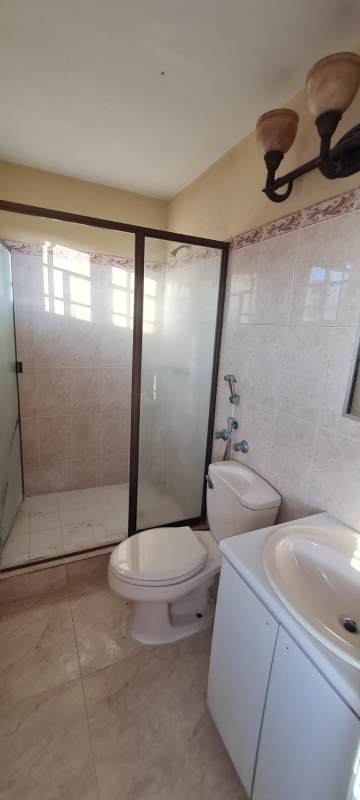 Bathroom with glass shower enclosure traditional marble-style tiles vanity in rental home Panama