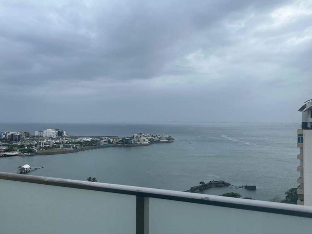 Contemporary living room with striped sofas, TV console, and access to balcony overlooking the Pacific