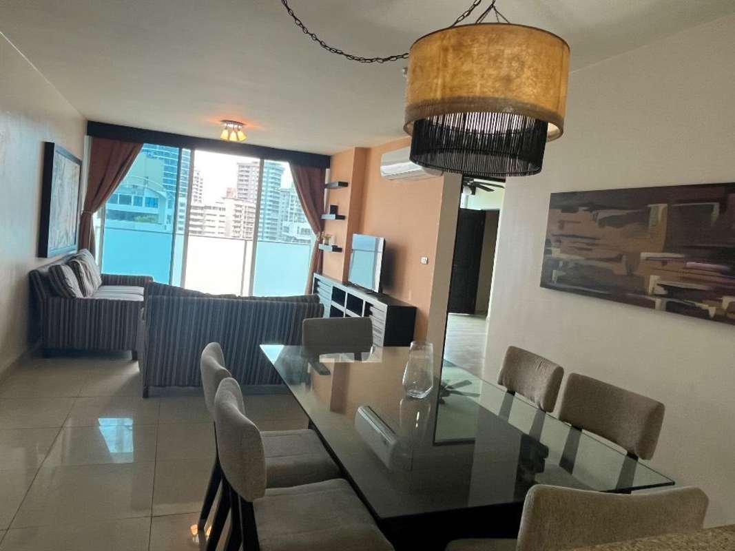 Bright living and dining area with large windows facing Panama City ocean skyline.