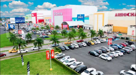 Colorful facade of Westland Mall with parking lot, palm trees and vibrant storefronts along Panamerican Highway in Arraiján Panama