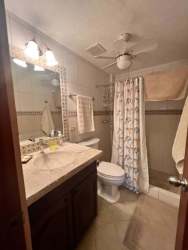 Traditional bathroom with beige tiles, large mirror, shower with colorful curtain in PH Malibu Beach