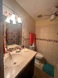 Bright bedroom with teal accent wall, tile flooring, ceiling fan and large window ocean view