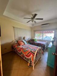 Bedroom with two twin beds, colorful bedding, large window, ceiling fan and AC at PH Malibu Beach
