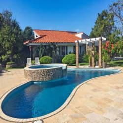 Mediterranean villa featuring terracotta roof, curved swimming pool, pergola and lush landscaping in Punta Barco Panama