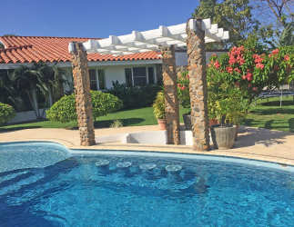 Mediterranean home exterior with swimming pool, pergola and lush garden landscaping in Punta Barco Village