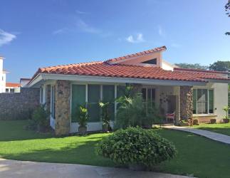 Single-story Mediterranean villa with red tile roof, stone accents, large windows and tropical garden in Punta Barco Panama
