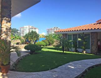 Mediterranean home exterior with stone facade, landscaped garden, curved path, tropical plants in Punta Barco Village Panama