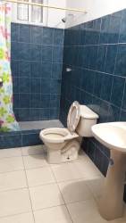 Simple bathroom with blue tiled walls, pedestal sink, shower with curtain in house for rent Chame Panama