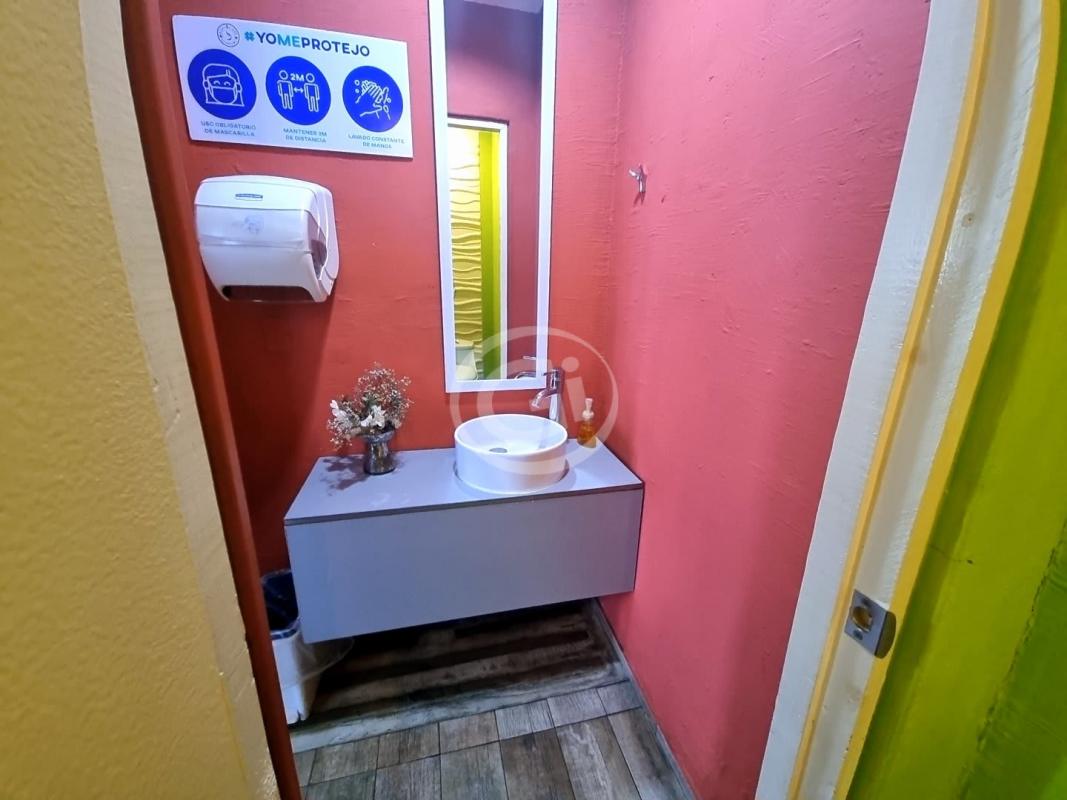Reception snack bar area with wooden counter, fridges, and indoor plants at PH Colores Bella Vista Panama City