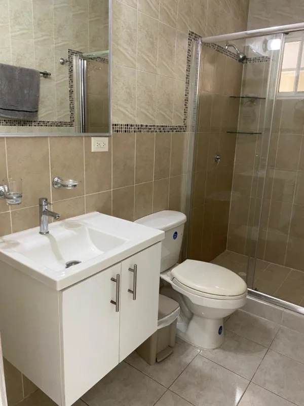 Modern bathroom with beige tiles, glass enclosed shower, vanity in Residencial Santa Fe Panama
