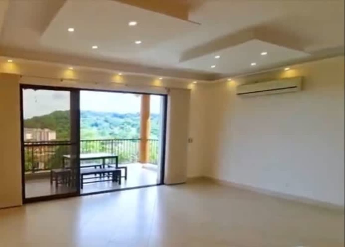 Bright furnished bedroom with wooden headboard, green bedding, large window overlooking greenery at PH Embassy Club Clayton Panama