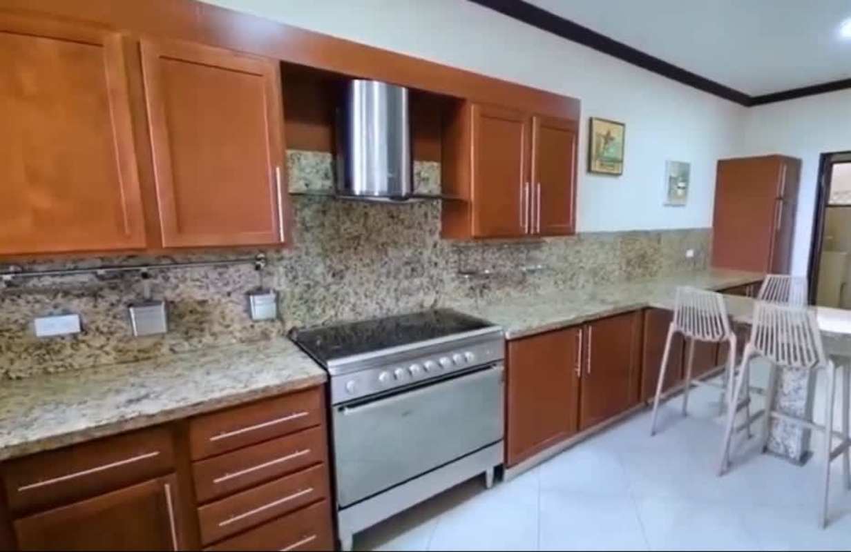 Modern kitchen granite countertops stainless steel appliances bar stools wood cabinetry Embassy Club Clayton Panama