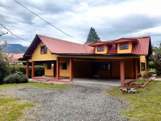 Two-story yellow house with balcony, front garden fence for sale in Volcán Panama