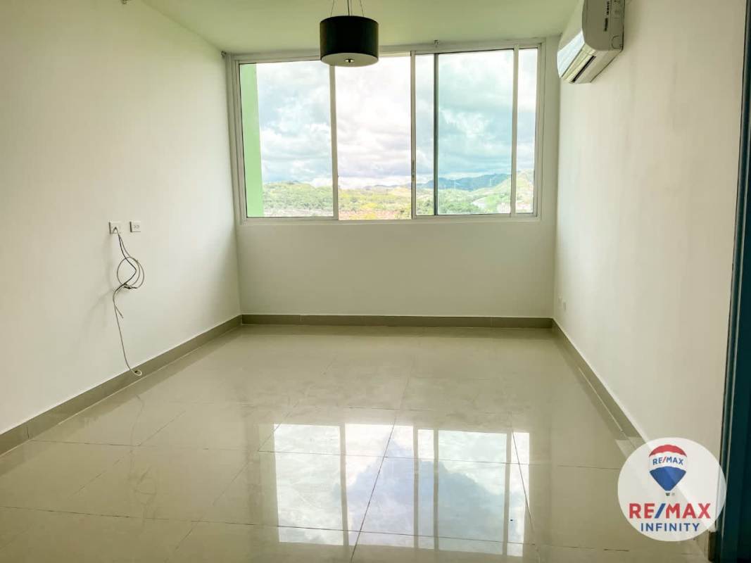 Empty living area with big window, AC unit and panoramic mountain-city view in Panama apartment