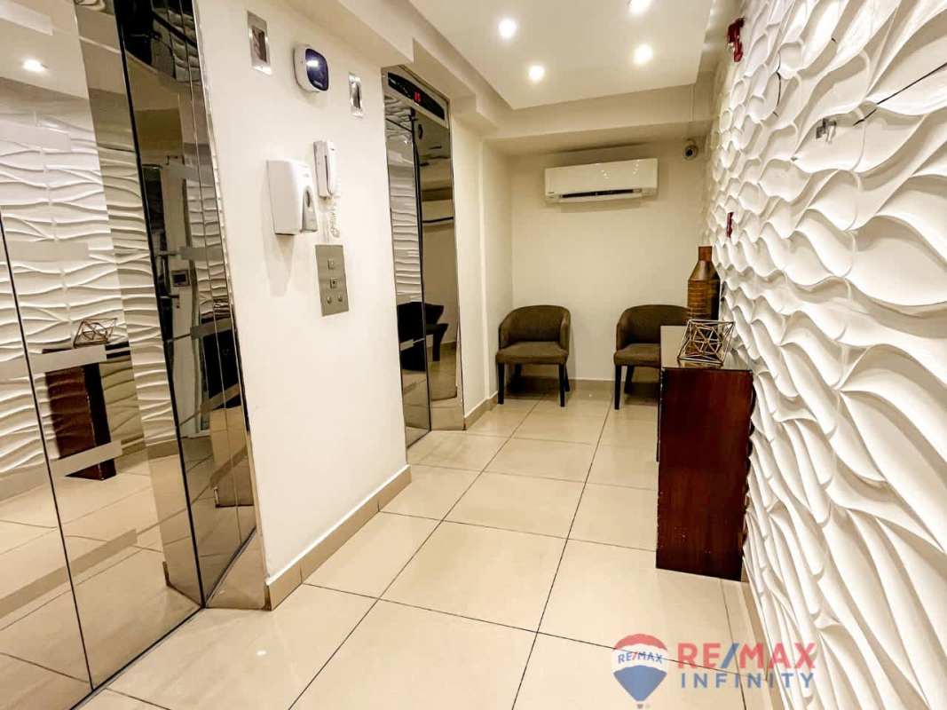 Lobby hall with elevators, textured wall panels and seating in Condominium Condado del Rey