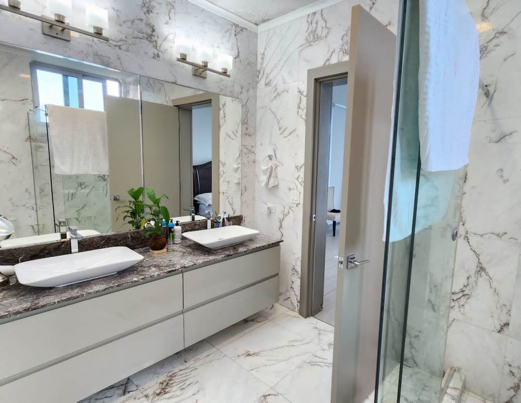 Contemporary bathroom with marble walls and floors, double vanity, glass shower in PH Mirador Costa del Este Panama