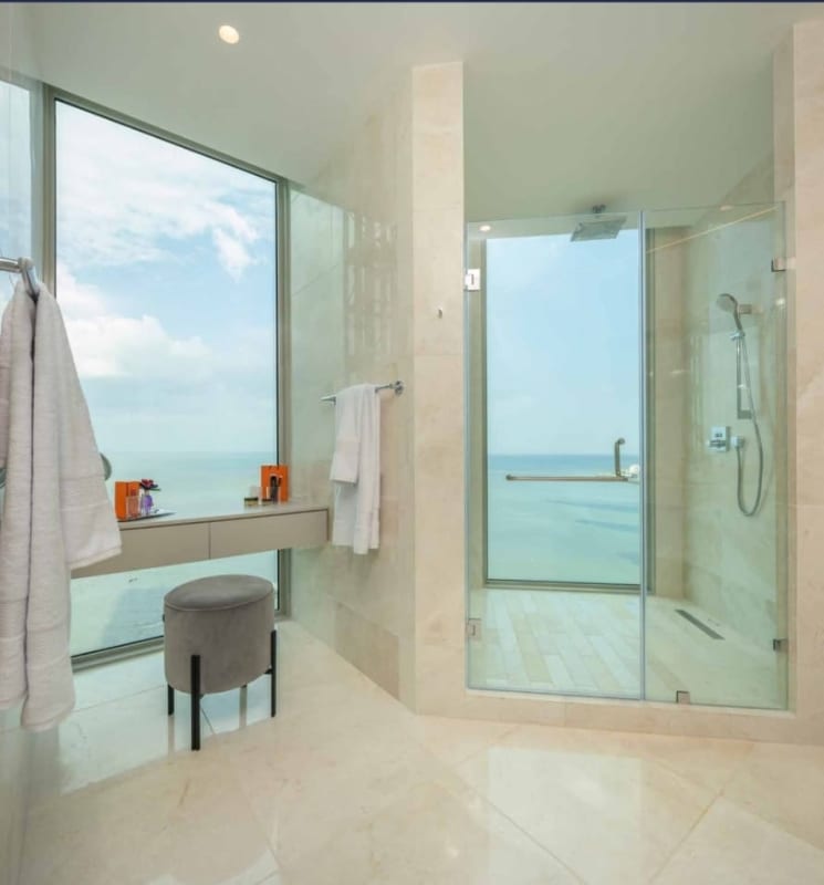 Luxury bathroom with marble tiles, glass shower, panoramic window overlooking ocean in Pacific Point Tower 400 Panama City