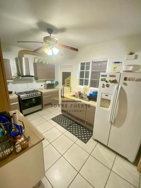 Modern kitchen with granite countertops, refrigerator and gas stove in Brisas del Golf house Panama