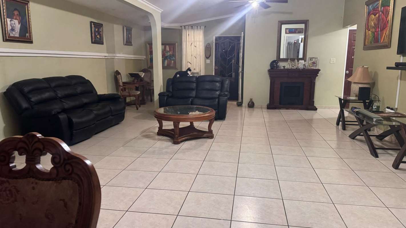 Spacious living room with tile floor, ceiling fan, and fireplace in Brisas del Golf Panama house for sale
