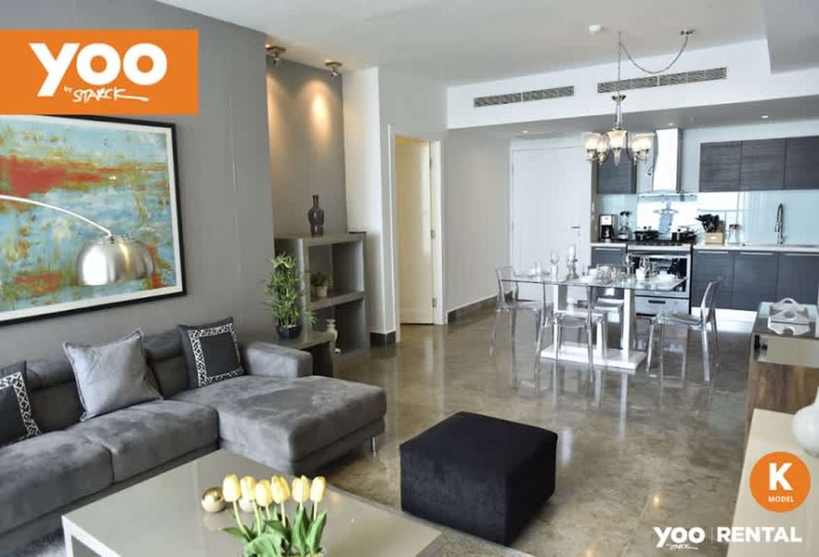 Bright open living and dining space with abstract art and gray sectional sofa at PH Yoo Panama