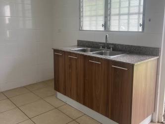 Compact modern kitchen with granite counter, stainless sink, wood cabinets in Brisas del Golf Arraiján Panama