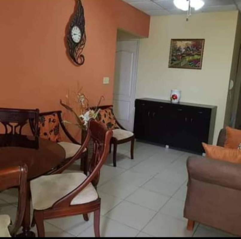 Dining area with wooden furniture, orange accent wall in apartment PH Campo Limberg Don Bosco