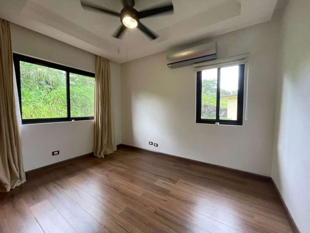 Spacious bedroom with wood flooring AC ceiling fan and garden views Embassy Club