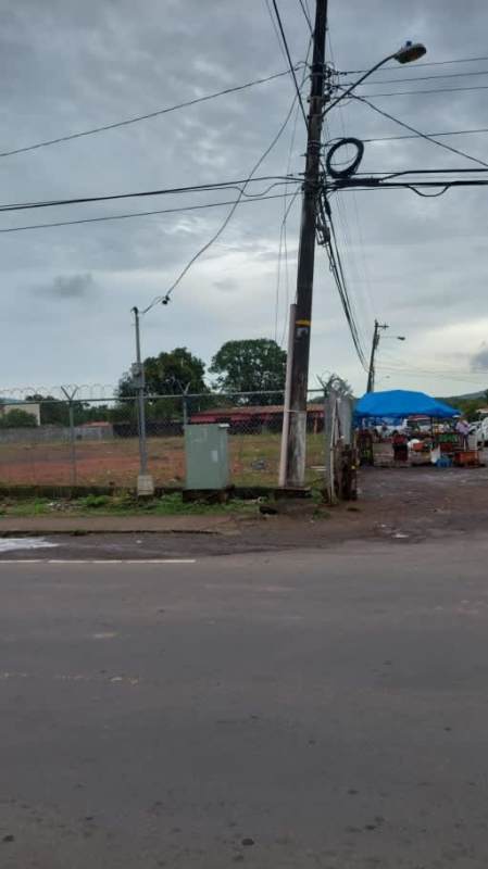 Corner lot fenced property with utility poles and nearby market La Chorrera Panama