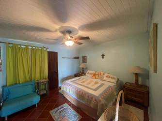Bedroom with ceiling fan wood ceiling terracotta floors beachfront villa Farallón Panama