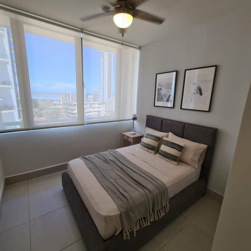 Modern bedroom with upholstered bed, large window with cityscape view at PH Riverside Panama
