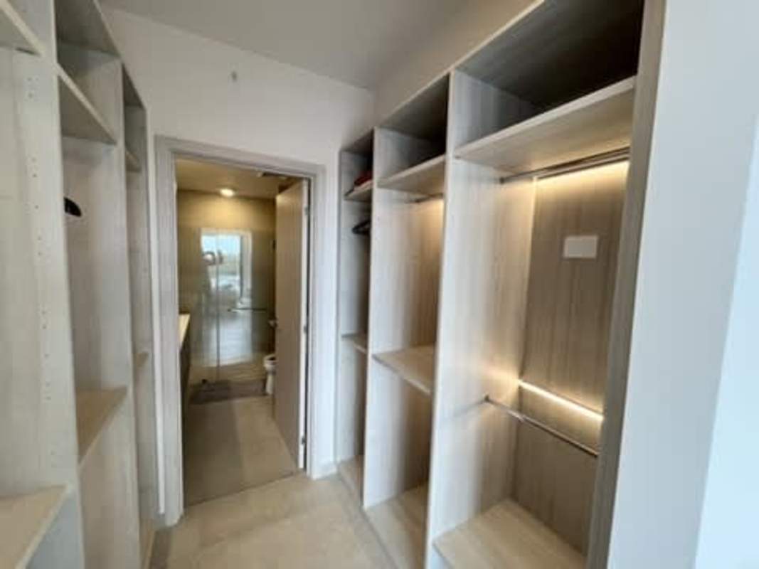 Spacious walk-in closet with custom cabinetry leading to bathroom