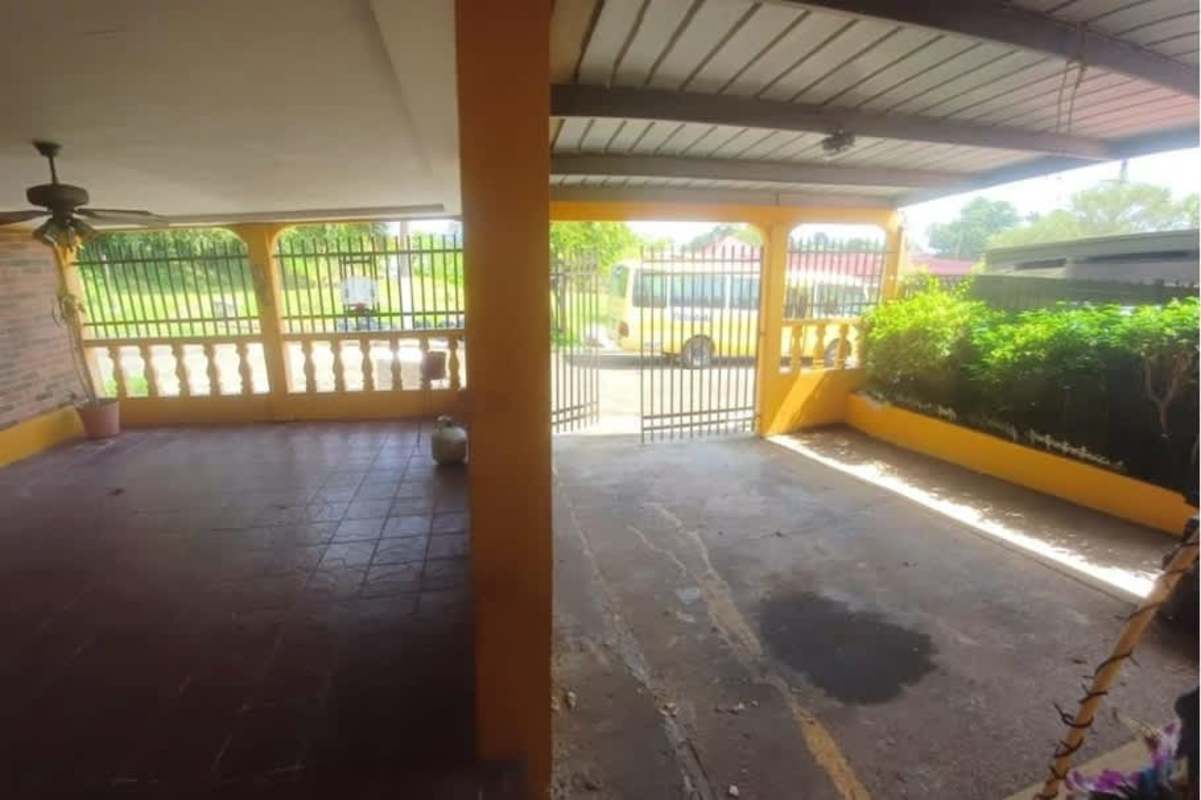 Basic galley kitchen with cabinets, refrigerator, stove, tiled walls at Cerro Viento Panama City house.