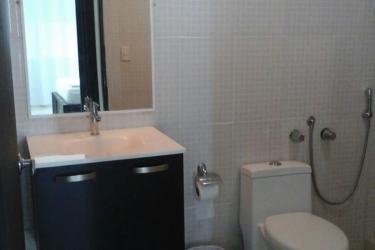 Minimalist living room with black sofa, TV, light decor and natural light at Playa Corona Suites Panama