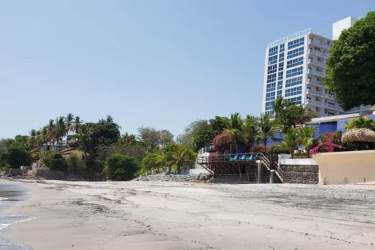 Modern bathroom with sink vanity, toilet, wall mirror, and tiled walls in Playa Corona Suites Panama